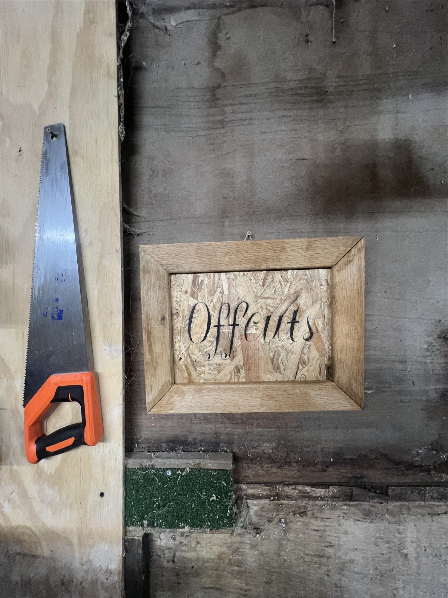 A hand-lettered Offcuts workshop sign in an oak frame